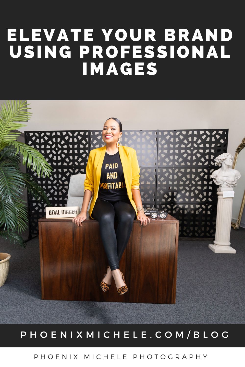 black woman with a black t-shirt and yellow blazer sitting on top of a brown office desk